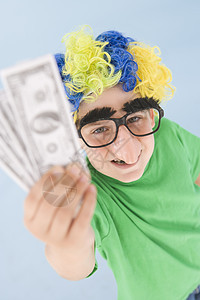 年轻男孩戴小丑假假发和假鼻子 拿着钱图片