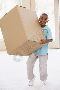 年轻男孩在新家拿着盒子 微笑着笑着抵押男性小男孩财产公寓阶梯购买者家具相机斗争图片