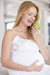 孕妇吃苹果 笑着微笑怀孕小吃新妈妈面包享受饮食女性待产水果妈妈图片