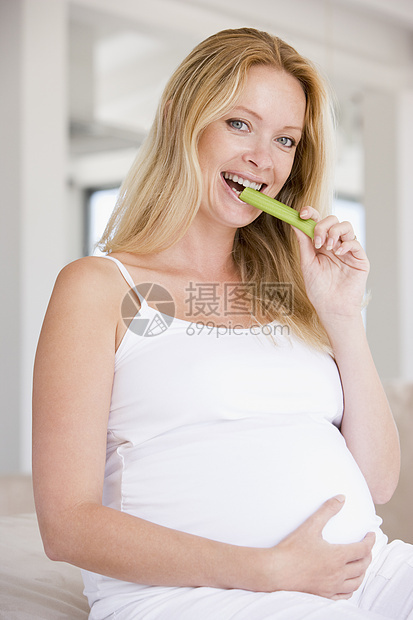 孕妇吃着心菜和微笑女性孕产孕妇装妈妈享受小吃相机芹菜饮食家长图片