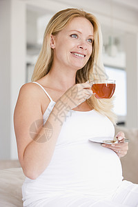 带着茶杯微笑的孕妇享受家长怀孕孕产妈妈一杯茶孕妇装家庭女性饮食图片