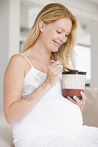 怀着一桶冰淇淋微笑的孕妇准妈妈怀孕待产享受孕妇装孕产女性妈妈新妈妈饮食图片