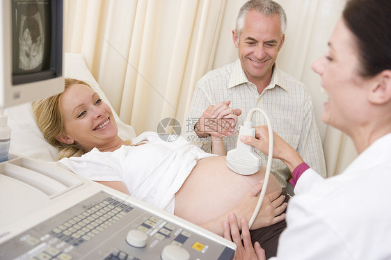 孕妇从有丈夫手表的医生那里得到超声波检查考试检查女士男人女性准妈妈扫描孕妇装怀孕卫生图片