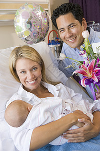 新母亲带着婴儿和丈夫在医院中微笑的笑容病房相机男性访问拜访产房妈妈新生怀孕新妈妈图片