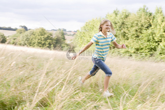 年轻女孩在田里微笑地奔跑图片
