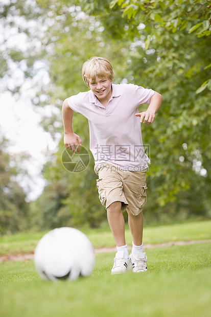 年青男孩踢足球享受小男孩乐趣公园男生花园玩家孩子运动足球图片