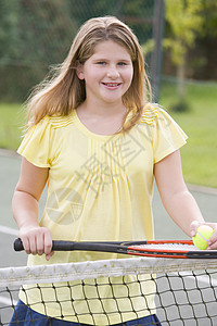 在网球场上笑着拍打的年轻女孩享受运动游戏网球乐趣童年法庭球拍女性播放器图片