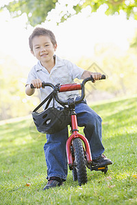 在户外骑自行车的小男孩微笑着公园男生相机安全帽享受农村男性骑术乐趣训练轮图片