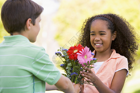 年轻男孩给年轻女孩送鲜花和微笑女朋友男生男朋友男性情感朋友们花朵花束两个人孩子图片