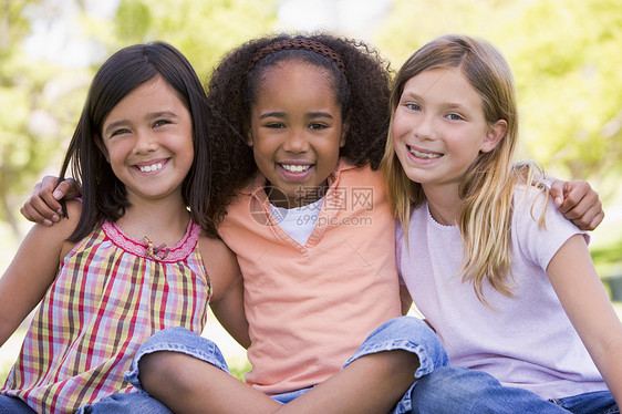坐在户外微笑的三名年轻女孩朋友拥抱水平友谊女孩们孩子女性相机农村女朋友闺蜜图片
