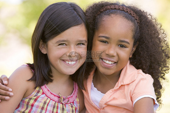 两个坐在户外微笑的年轻女孩朋友图片