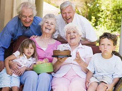 祖父母和孙子孙儿孙女在有蛋糕和礼物的院子上图片