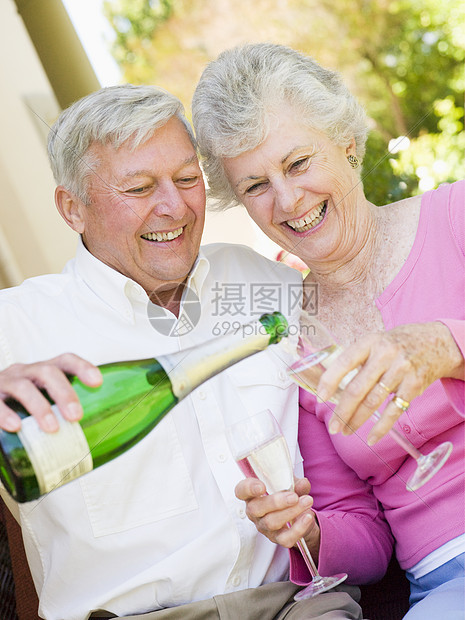 情侣在院子上 喝香槟和微笑图片