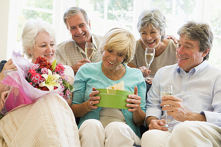 五位朋友带着香槟和礼物在客厅里微笑着笑丈夫男人友谊情感女士退休男性老年朋友们女性图片