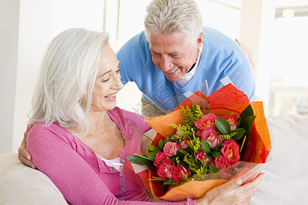 丈夫给妻子送花和微笑男性礼物生日浪漫女士情感沙发男人长椅客厅图片