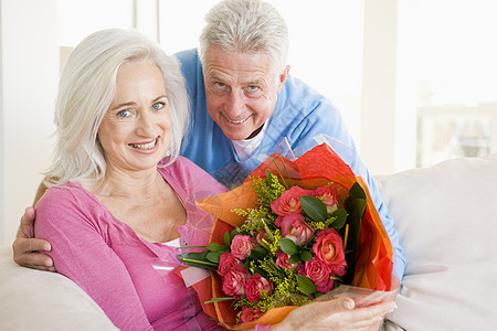 丈夫和妻子拿着鲜花 微笑着笑容惊喜亲热礼物女性伙伴展示长椅感情生日盒子图片