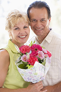 丈夫和妻子拿着鲜花 微笑着笑容花束生日情感纪念日两个人中年场合周年客厅男人图片