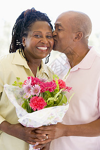 丈夫和妻子带着鲜花亲吻和微笑中年礼物场合退休女士情感男人伙伴惊喜展示图片