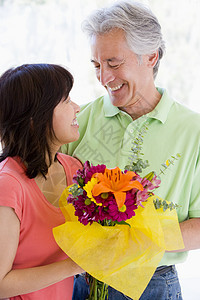丈夫和妻子拿着鲜花 微笑着笑容展示女士礼物中年两个人感情退休周年伙伴夫妻图片