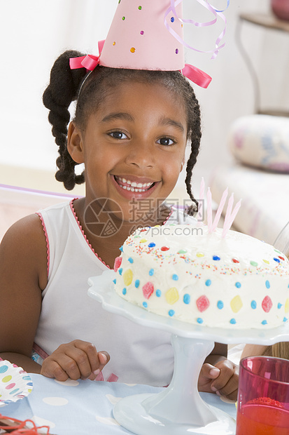 年轻女孩戴着帽 在她微笑的面前吃蛋糕图片