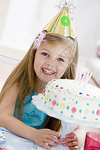 年轻女孩戴着晚礼帽 生日蛋糕笑着微笑桌子女性蜡烛孩子们派对相机生日孩子食物图片