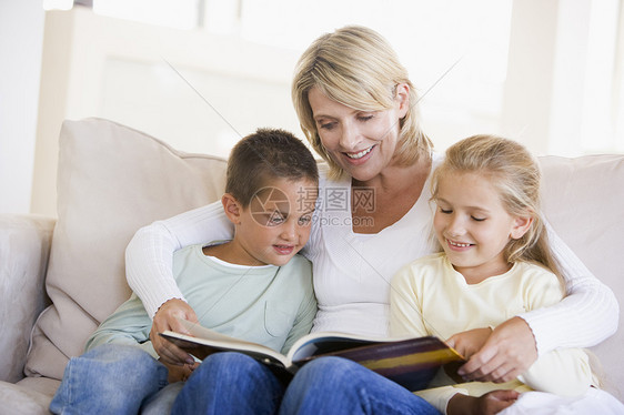 妇女和两名儿童坐在起居室阅读书上休息室家庭儿子家庭生活故事孩子沙发孩子们男生拥抱图片