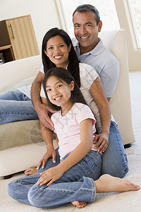 家庭在客厅里微笑地笑着女孩沙发三个人孩子们感情爸爸休息室母亲团体父亲图片
