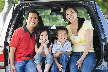 家庭坐在面包车后面微笑的笑容女性儿子商务车成人男人女儿旅行兄弟树干相机图片