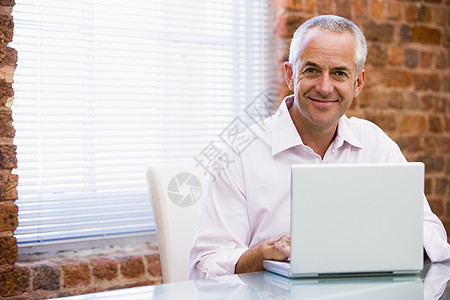 坐在办公室的商务人士微笑着笔记本电脑图片