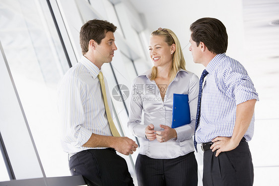 三个商务人士站在走廊里聊天和笑着说话的三位商务人士图片