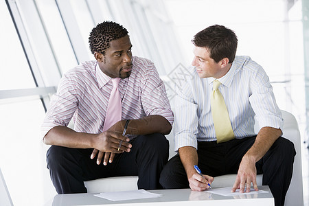 坐在办公室大厅前厅的两位商务人士在聊天和微笑团队两个人商业会议合作中年水平同事伙伴男人图片