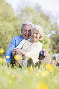 一对在户外放松的情侣微笑着夫妻女士相机两个人野花男性女性毛茛农村退休图片