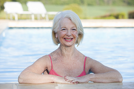 在户外游泳池中微笑着的女子水平游泳衣女士女性退休享受相机游泳图片