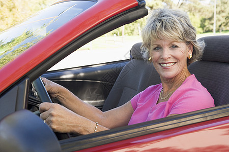 坐在可兑换汽车上的妇女笑着敞篷车摩托车女性微笑女士水平享受农村退休软顶图片
