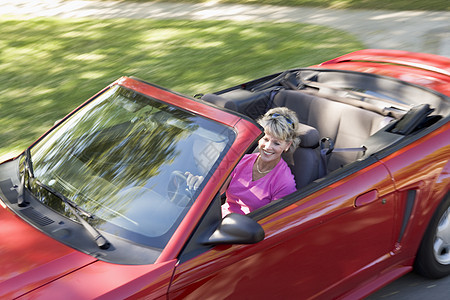 坐在可兑换汽车上的妇女笑着软顶速度摩托车微笑敞篷车女士运动退休女性农村图片