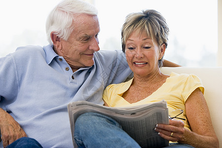在客厅的一对夫妇阅读报纸微笑图片