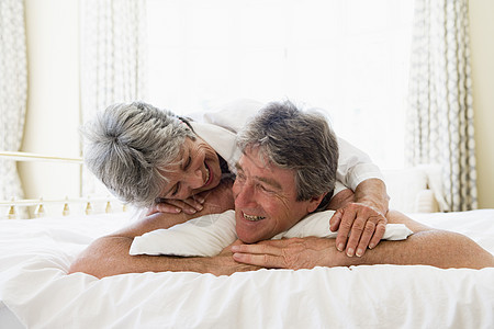 夫妻在卧室放松和微笑退休水平女士两个人感情妻子女性苏醒睡衣男人图片