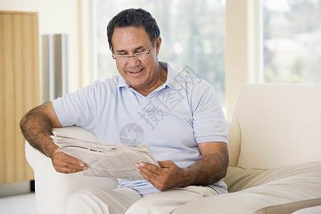 男人在客厅看报纸笑着看报纸退休休息室阅读男性牙裔眼镜沙发微笑长度时事图片