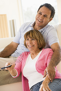 在客厅的一对夫妇 遥控器笑着丈夫两个人夫妻男人牙裔男性团结长椅女性退休图片