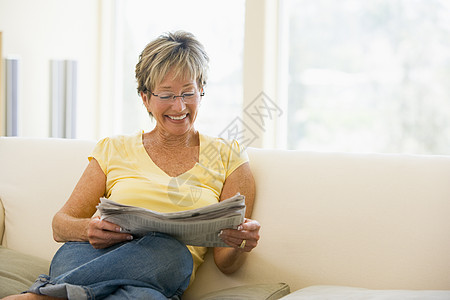 妇女在客厅的报纸上微笑着笑着放松图片