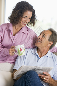 一对夫妇在报纸上笑着放松亲密感休息室咖啡团结夫妻丈夫沙发长椅两个人女性图片