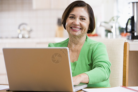 厨房里的女人带着笔记本电脑的微笑银色技术水平网络女士女性互联网冲浪者成人婴儿图片