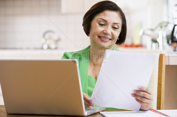 厨房里的女人带着笔记本电脑和文件微笑文档账单水平婴儿技术女士女性阅读拉丁成人图片