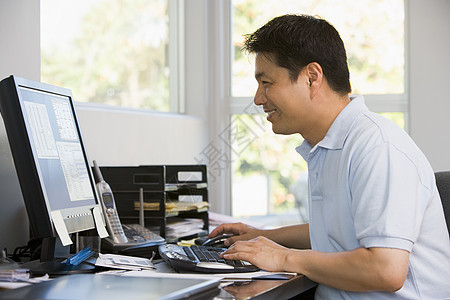 在家用电脑和微笑的办公室里的男人水平中年工作站婴儿潮桌子成人男性技术图片