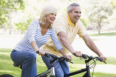 一对在户外骑自行车的夫妇微笑着男人男性婴儿潮男朋友公园享受中年女性骑术两个人图片