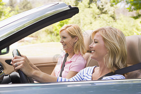 坐在可兑换汽车上笑着笑着的两名妇女图片