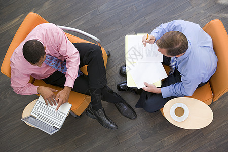 两名商务人士用咖啡笔记本电脑和文件夹坐在室内门厅男人一杯茶工作男性阅读会议商业两个人办公室图片