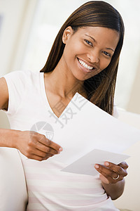 妇女在起居室中笑着阅读文件邮件家庭世代微笑长椅女性成人长度中年沙发图片