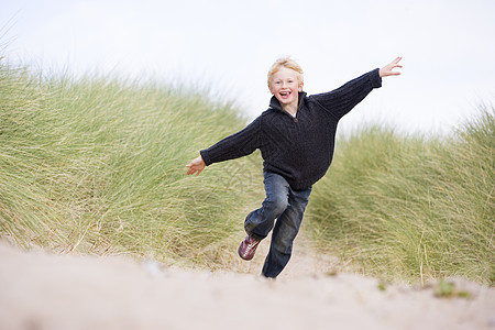 在海滩上微笑的年轻男孩低角度自由视图男性孩子们中年视角沙丘踪迹季节图片