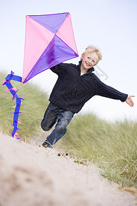 小男孩在海滩上奔跑 风筝微笑视图踪迹中年男性衣服跑步视角季节享受沙丘图片